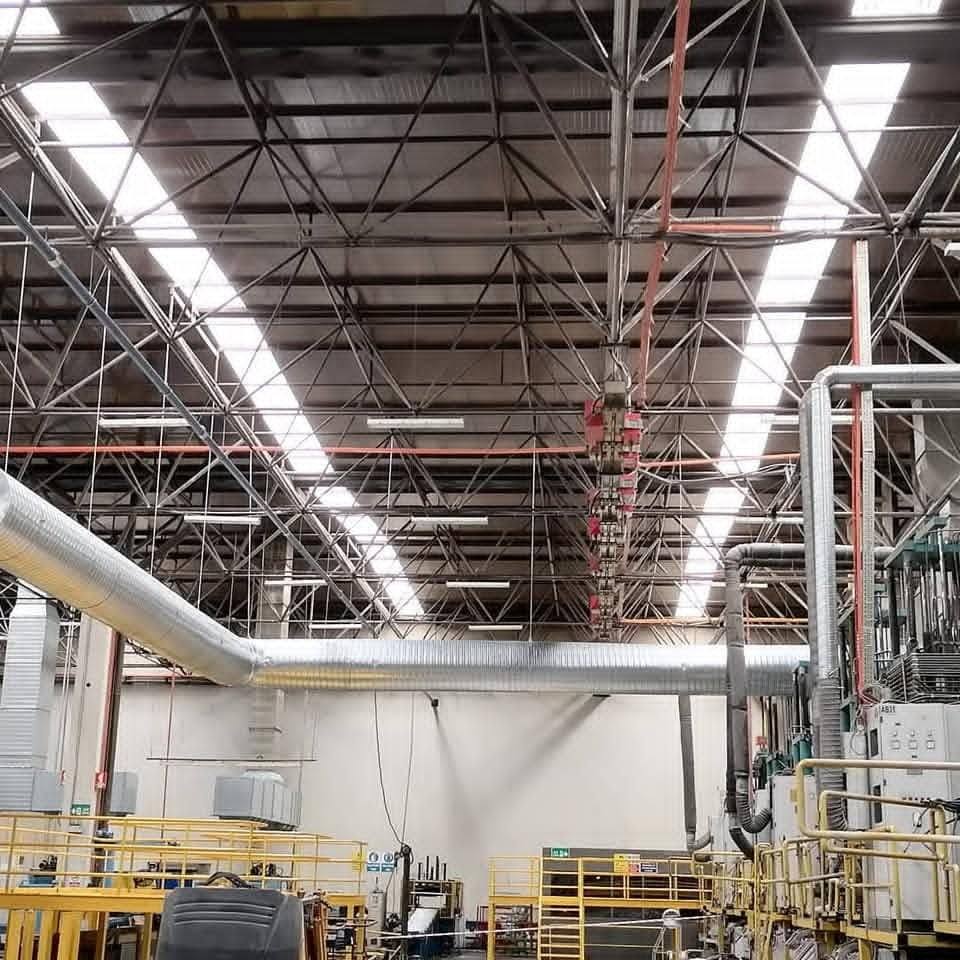 Fabrika üretim holünde tavan boyunca uzanan galvaniz spiral havalandırma kanalı